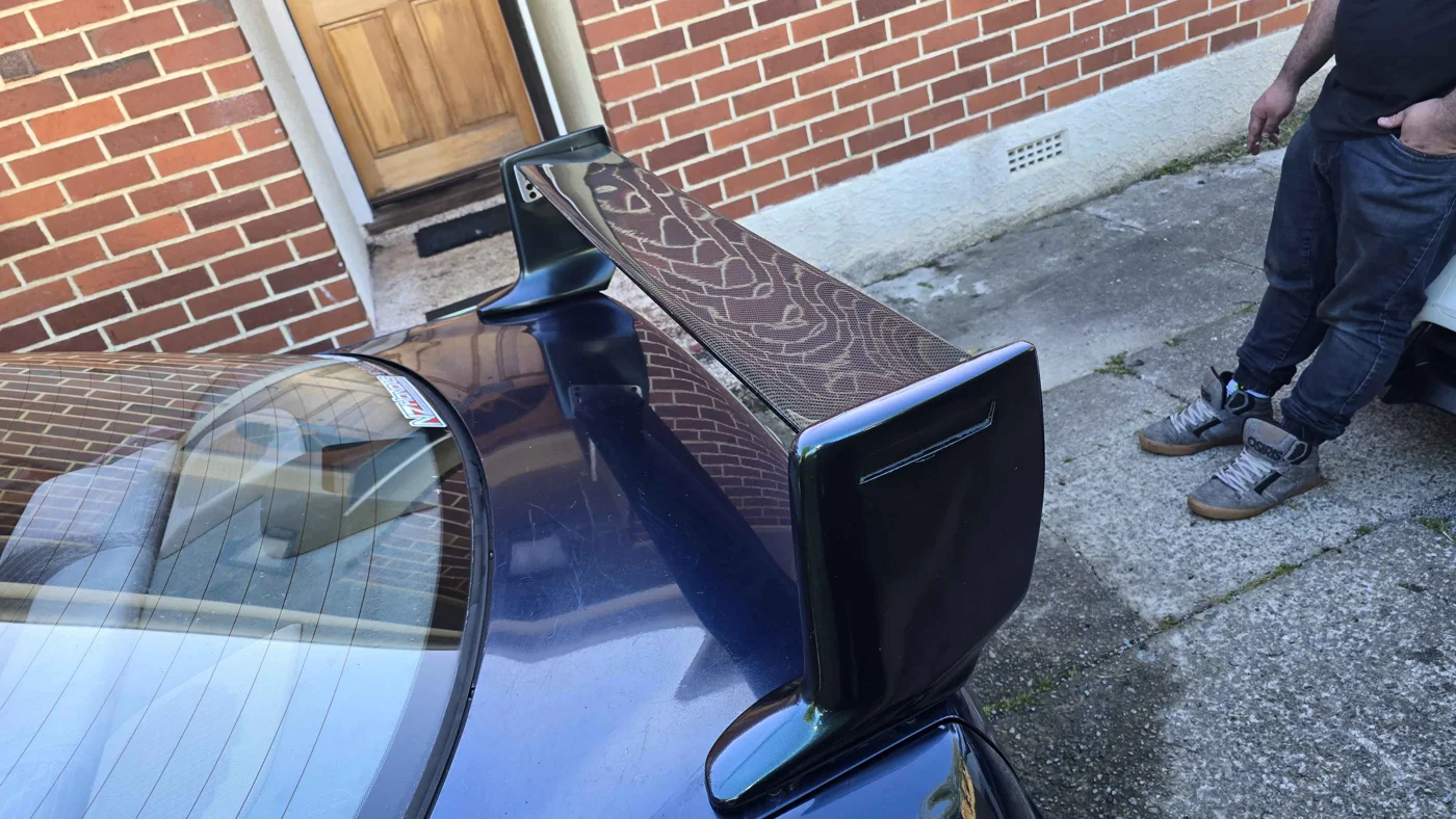 Carbon fibre rear wing fitted to a blue car
